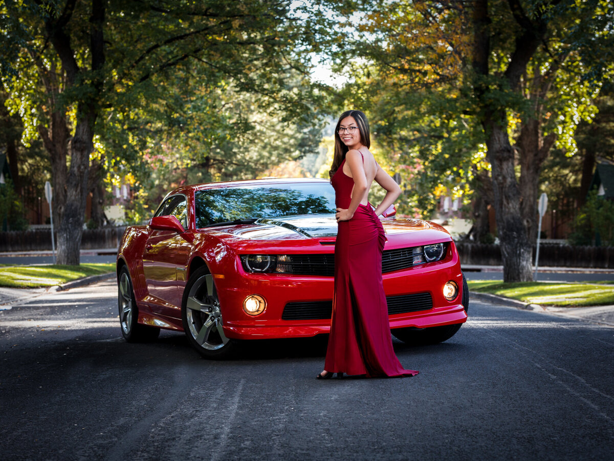 Elegant senior portrait with burgundy gown and red Camaro